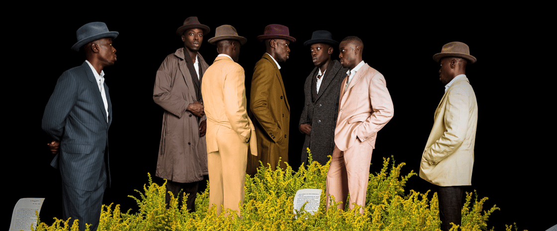 People gathering with earthy tone suits in front of black background.